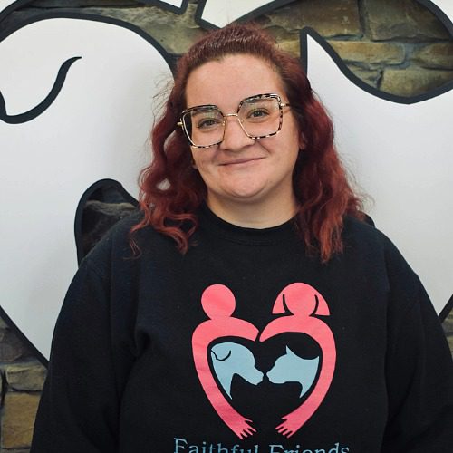 Lex - female with square glasses and red hair wearing a logo branded shirt for Faithful Friends